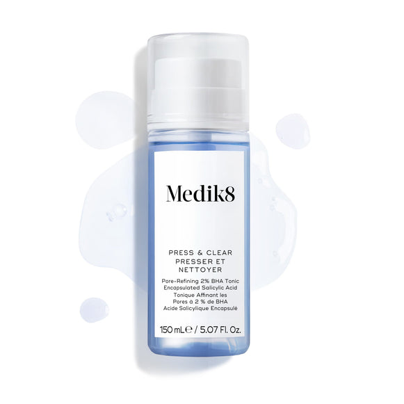 Fľaštička Medik8 Press & Clear (150 ml) zobrazená na bielom pozadí s kvapkami modrého tonika okolo nej.-18