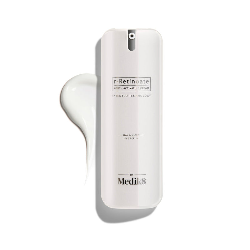 Biela pumpičková fľaštička r-Retinoate Day & Night Eye Serum s kvapkou produktu vedľa nej.
