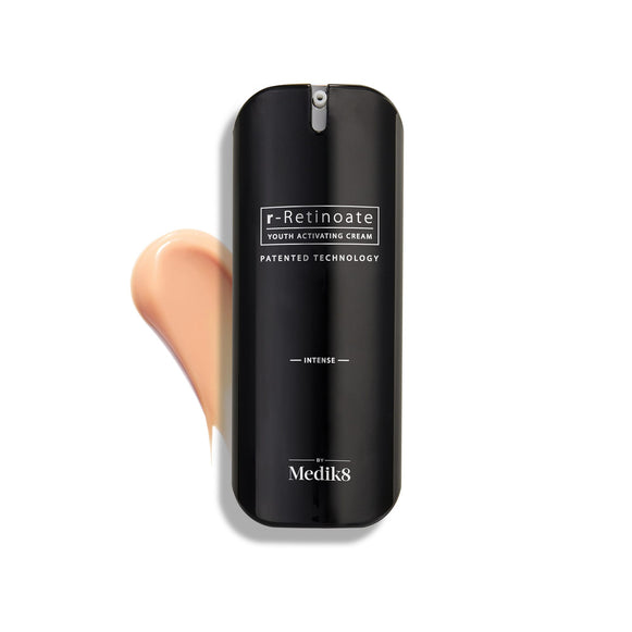 Fľaštička Medik8 r-Retinoate Intense Youth Activating Cream je zobrazená na bielom pozadí s viditeľným vzorkom broskyňovo sfarbenej krémovej textúry za ňou.
-38