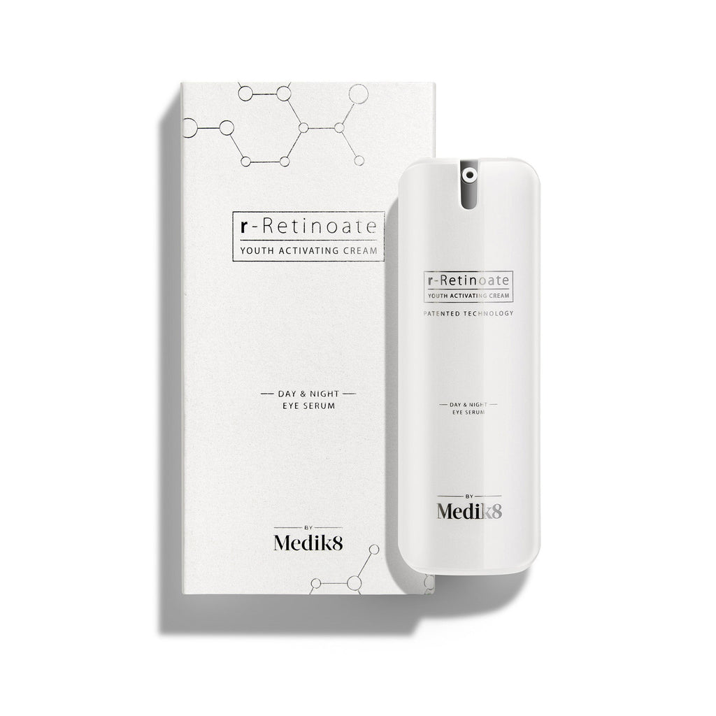 Biela pumpičková fľaštička r-Retinoate Day & Night Eye Serum stojí vedľa zodpovedajúcej bielej kartónovej škatuľky.
