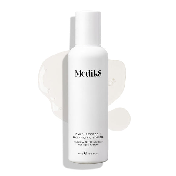 Fľaštička tonika Medik8 Daily Refresh Balancing Toner s objemom 150 ml stojí na bielom pozadí s rozliatou čírou tekutinou, pričom text na obale produkt definuje ako hydratačné pleťové kondicionérium s kvetinovými vodami (Hydrating Skin Conditioner with Floral Waters).-18