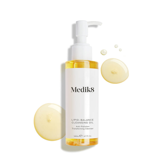 Fľaštička Medik8 Lipid-Balance Cleansing Oil stojí na bielom pozadí. Zlaté kvapky oleja ju obklopujú a zvýrazňujú jej bohatú, tekutú textúru.
-22