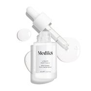 Priehľadná sklenená fľaštička séra Liquid Peptides je zobrazená s vybratým kvapkadlom, ktoré leží vedľa nej spolu s kvapkami séra, ktoré detailne ukazujú jeho tekutú textúru.