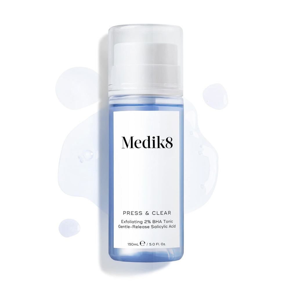 Fľaša Medik8 Press & Clear (150 ml) na bielom pozadí, okolo ktorej sú rozstreknuté kvapky modrého tonika. Text zdôrazňuje zloženie  Exfoliating 2% BHA Tonic.