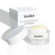 Otvorený kelímok krému Daily Radiance Vitamin C je zobrazený pred kartónovým obalom produktu, pričom je viditeľná textúra krému.

