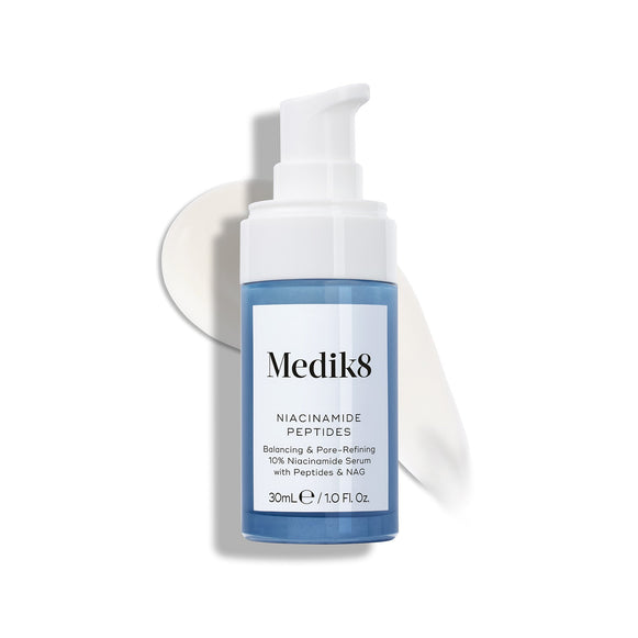 Fľaštička séra Medik8 Niacinamide Peptides s bielou pumpičkou leží na bielom podklade, pričom za ňou je viditeľná rozotretá vzorka bielej krémovej textúry tohto séra.-12