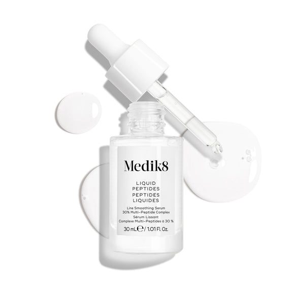Číra sklenená kvapkacia fľaštička séra Liquid Peptides je zobrazená s odstránenou pipetou položenou vedľa nej a kvapôčkami séra, ktoré znázorňujú jeho textúru.-11