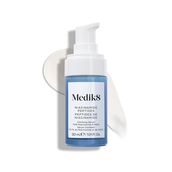 Fľaštička séra Medik8 Niacinamide Peptides s bielou pumpičkou stojí na bielom povrchu s pásikom bieleho séra za ňou.-25