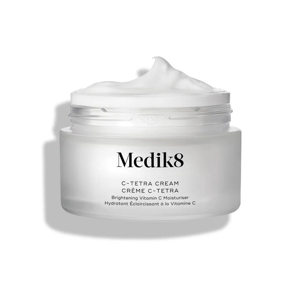 Otvorený kelímok krému Medik8 C-Tetra Cream je zobrazený na čistom bielom pozadí s jemnými tieňmi. Biely matný sklenený kelímok obsahuje logo Medik8 a označenie „C-TETRA CREAM Vitamin C  vo veľkosti 50 ml. Na vrchu kelímka je viditeľný hustý vírivý ťah bieleho krému, ktorý zvýrazňuje jeho hydratačnú textúru.-22